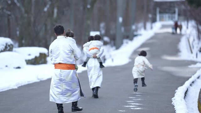 Snow blankets a quiet winter path. Children dash ahead, joyful and carefree. Adults follow, bundled in white coats. Gentle, peaceful winter scene unfolds. Perfect for holiday, family