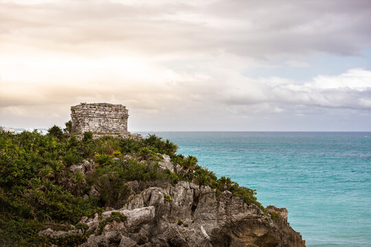 Temple of the Wind God on a rocky cliff overlooking the turquoise Caribbean Sea in Tulum, Mexico