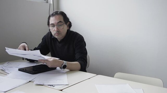 Tired male office worker or teacher taking off glasses and rubbing face in extreme exhaustion at desk