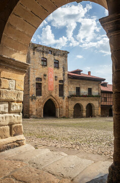 Santillana del Mar, Spain - July 30, 2024: View of the Plaza Mayor and the Torre de Don Borja Cultural Center building, framed by an arcade, in Santillana del Mar, Spain.