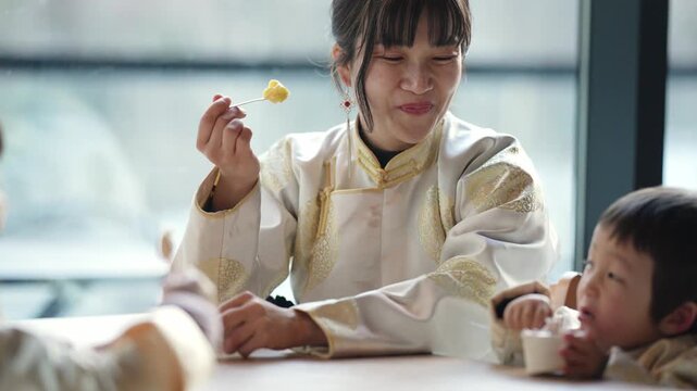 Young woman smiles as she eats with children. Children sit at table, eating together. Warm, joyful mealtime with family or group. Ideal for scenes of community or nurturing moments