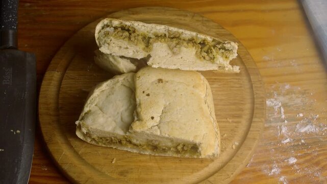 Close up of homemade rustic bread filled with savory meat stuffing on a cutting board