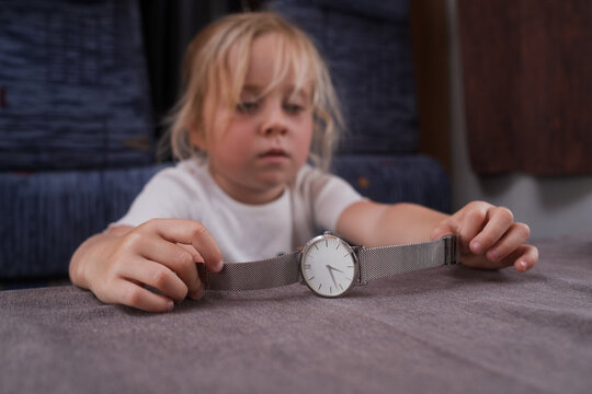 child waiting and looking at a classic watch on a table during a family motorhome road trip. 