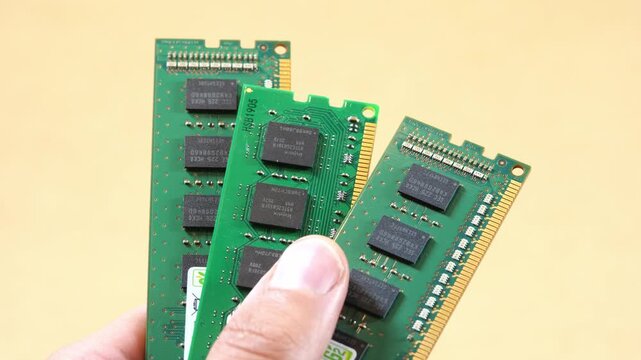 Hand fanning three green RAM memory sticks, closeup technology concept for desktop PC upgrade, component scarcity, semiconductor price increases and growing AI computing demand