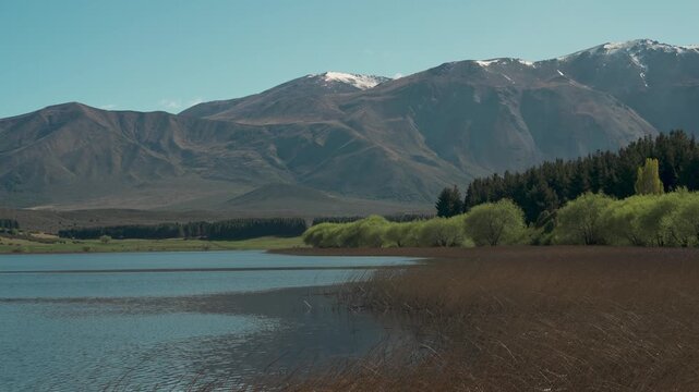 Panoramic landscape view of the calm waters of Laguna La Zeta, bordered by dense forest and dramatic mountains, Esquel, Chubut, Argentina.