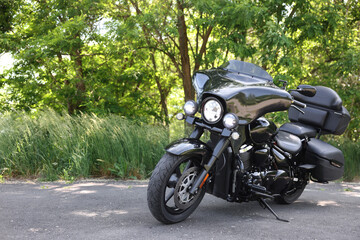 Fototapeta premium Modern black motorcycle parked on road outdoors, space for text