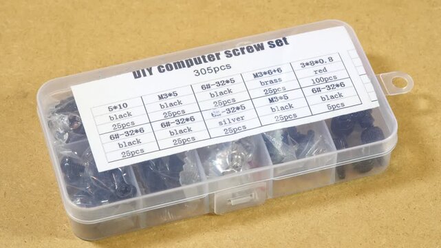 Transparent 305-piece DIY computer screw assortment box with labeled compartments, close-up panning video of black, silver, brass and red fasteners for electronics repair, upgrades and right to repair