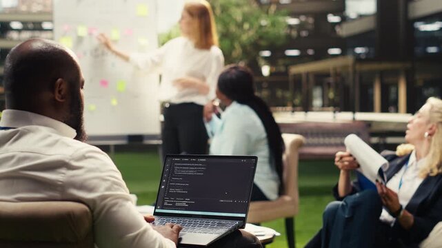 Black software developer working on programming code on laptop during outdoor workshop for business development, cloud computing software in IT department on terrace, for business planning.