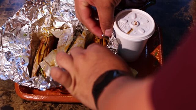 Person unwrapping authentic mexican birria tacos with consomme