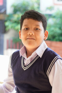 Asian school boy portrait with calm expression wearing uniform. Natural light and soft background. Education, childhood, identity, school concept.