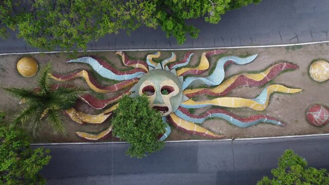 Vista a&eacute;rea cenital con movimiento dolly out con dron de una gran escultura colorida en forma de sol en un andador peatonal urbano en Cuernavaca, M&eacute;xico.