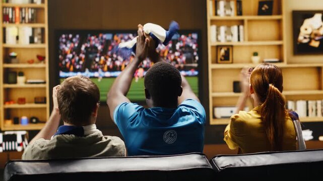 Football fan leader at home recreates a stadium experience with megaphone and drum to cheer for the team as passionate soccer supporters make loud noise with fan props in an apartment.