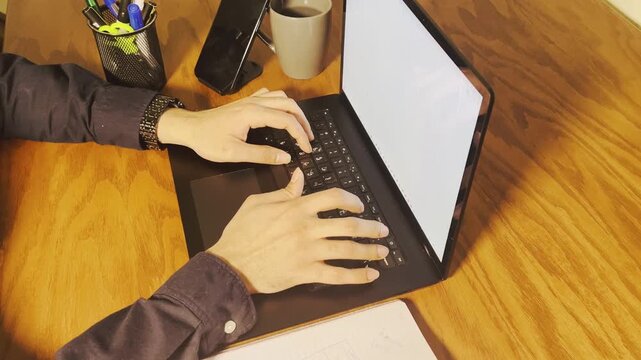 Person typing on laptop, overhead view of working at wooden desk, horizontal office lifestyle footage