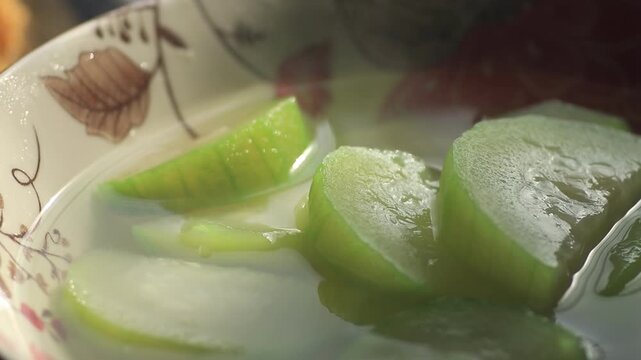 Close up view of freshly sliced green gourd squash soup with rising steam inside a traditional patterned ceramic bowl