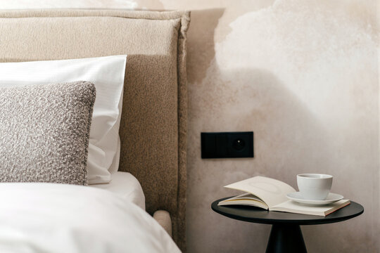 Decorative pillows and cushions on bed in hotel room with a side table