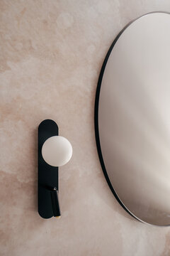 Modern minimalist mirror and wall sconce in a contemporary bathroom