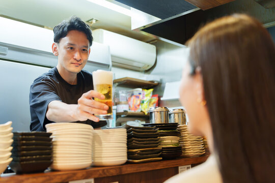 居酒屋でお客様にビールを提供する店長