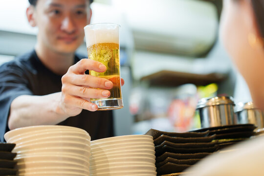 居酒屋でお客様にビールを提供する店長