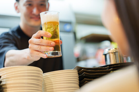 居酒屋でお客様にビールを提供する店長