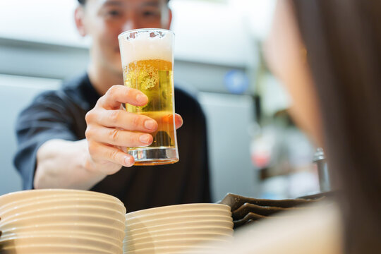 居酒屋でお客様にビールを提供する店長