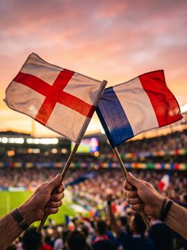 Fans wave England and France flags at a sporting event during sunset