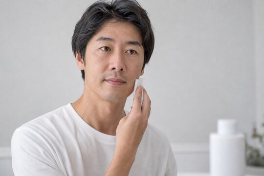 無地ボトルを見ながら美容液を確認する男性