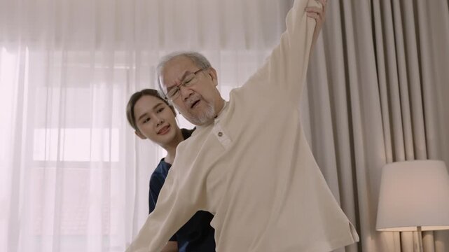 Professional beautiful Asian woman nurse physiotherapist helping senior man stretch arm and back for physiotherapy and rehabilitation of orthopedic conditions at hospital. Healthcare older concept. 