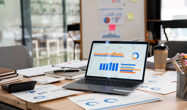 Laptop Displaying Financial Dashboard Data Graphs on Office Desk
