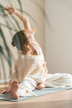 A woman doing yoga in her living room at home (relaxation, healthcare)