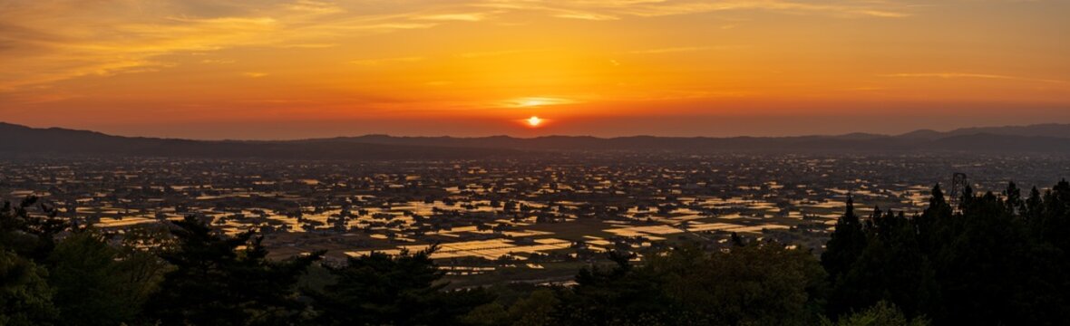 High-angle sunset view of the iconic Sankyoson dispersed settlement and flooded rice paddies in Toyama, Japan