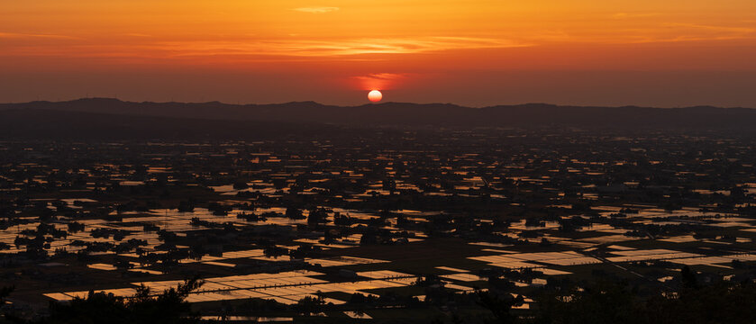 High-angle sunset view of the iconic Sankyoson dispersed settlement and flooded rice paddies in Toyama, Japan