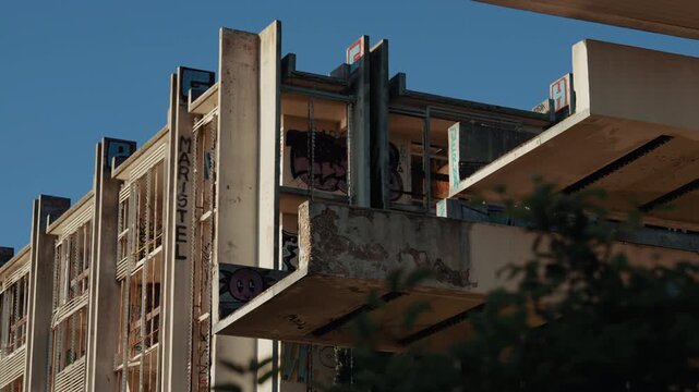 The abandoned Haludovo Hotel on Krk Island shows weathered concrete balconies, broken railings, graffiti-covered walls, and blue sky above the old resort.