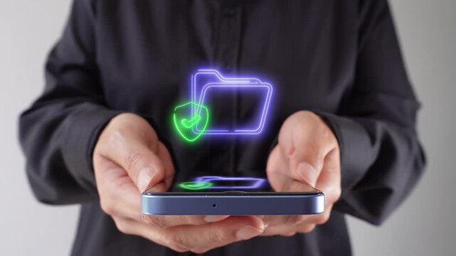 Hands hold phone with glowing folder and shield icon above screen. Visual suggests digital security or file protection concept