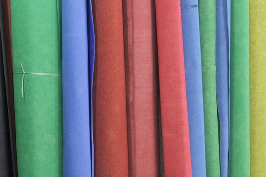 Colored rolls of fabric carpet arranged vertically on a shelf