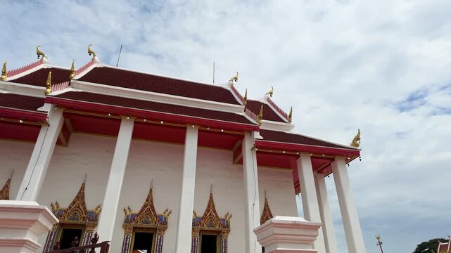 Traditional Thai Buddhist Temple Architecture with Red Roof and White Pillars
