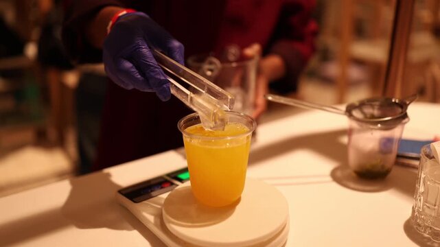 putting ice in a glass of orange juice on a weighing machine 