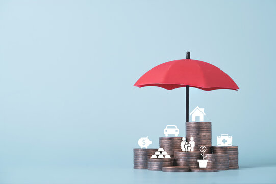 Red umbrella protecting stacks of coins with financial icons represents insurance coverage, wealth protection, financial security, risk management, investment planning and long term asset protection.