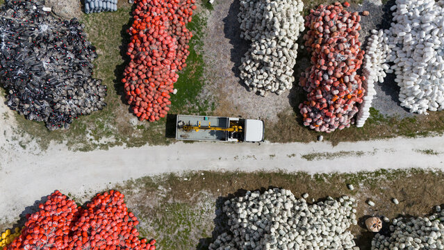 Aerial view of an open storage yard with white red and black fishing buoys. Equipment used for aquaculture and commercial fishing.