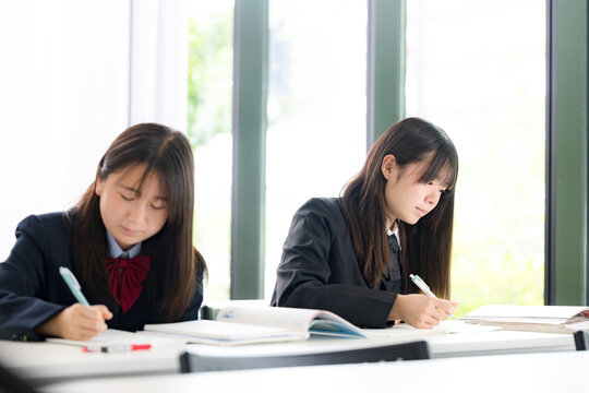 教室や塾で真剣に勉強へ取り組む日本人女子高校生　高校受験、大学受験の勉強や定期テスト対策のイメージ
