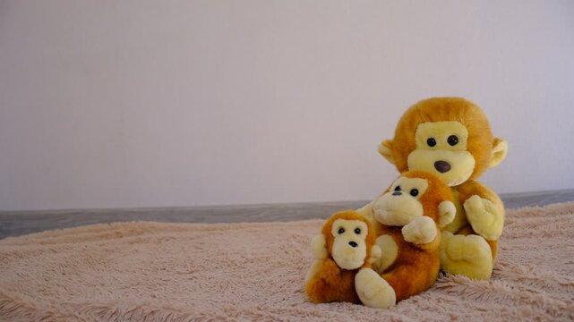 Cute stuffed toys, funny family of three monkeys sit in a group of warmth together on carpet, in the room created a relaxed and friendly atmosphere. Living room. Love, care, happy family concept.