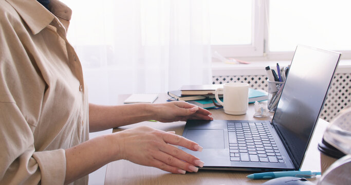 Home office. Freelancer workplace. Unrecognizable business woman preparing for paperwork at desk with notebook laptop indoor.