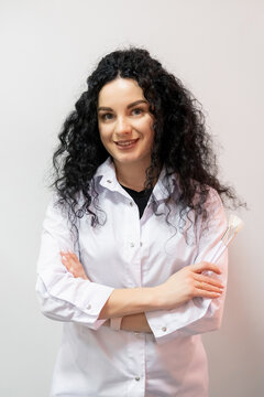 Professional cosmetician. Esthetician career. Smiling woman cosmetologist in white clinic uniform with facial brushes for beauty treatment.