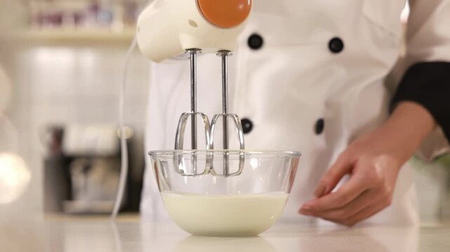 Pastry chef hand cooking process adds sugar and flour in white bowl whipping raw egg whites with butter with electric mixer beats for delicious birthday bakery order, baking, confectionery, culinary