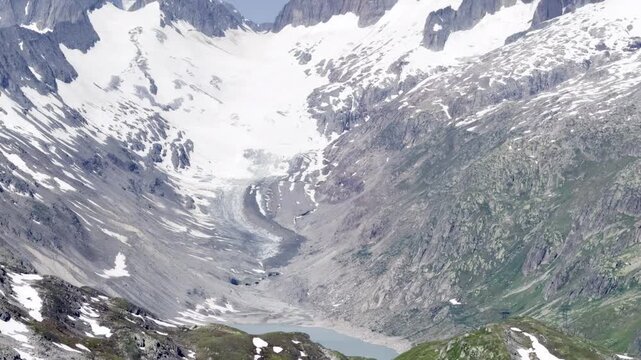 Aerial view zooming in on a retreating glacier and jagged snow-capped