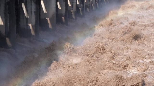 A slow-motion close-up of powerful floodwater discharging from a dam spillway
