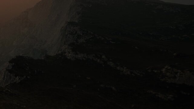 The scene shows mountains at dusk with dark tones. The sun sets in the background, casting long shadows on the rocky terrain, creating a dramatic atmosphere.