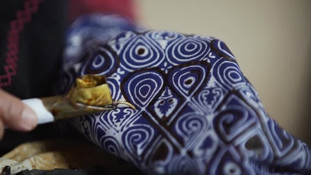 Traditional patterned fabric with intricate teardrop designs in deep purple.