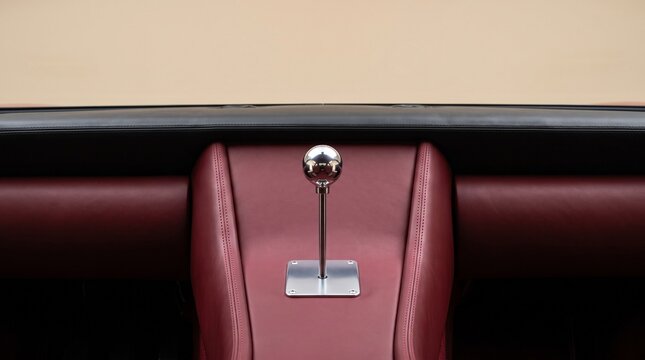 Polished chrome manual gear shifter mounted on a luxury maroon leather console, showcasing the elegant design and tactile gear selection for a premium driving experience.