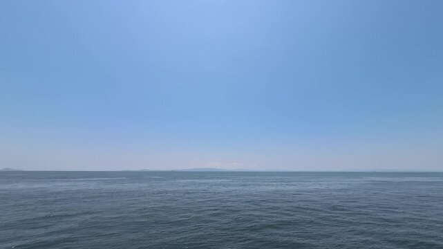 Cinematic video of a vast blue ocean with distant islands on the horizon under a clear sunny sky
