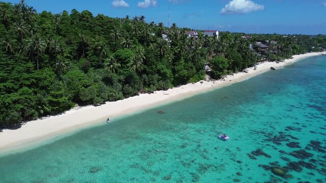 Aerial drone footage of paddleboarding at a tropical beach and coastal village in Sabang, Aceh, Indonesia.